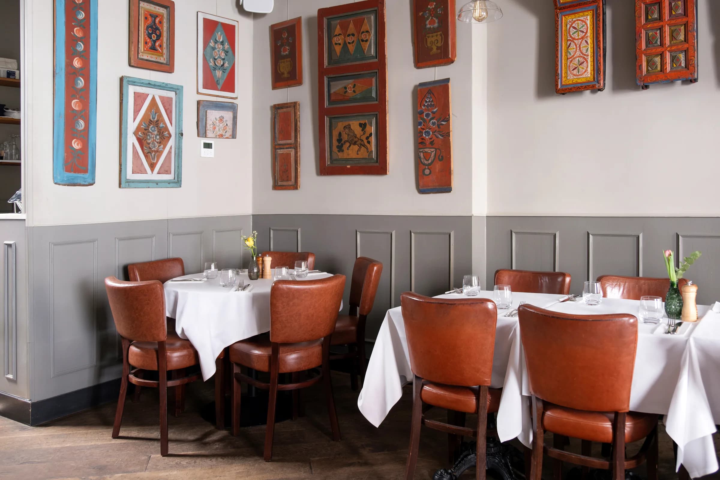 ZIMA first-floor dining room with set tables and folk art, Soho